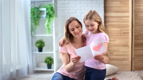 Child Gives Handmade Card to Mother Indoors
