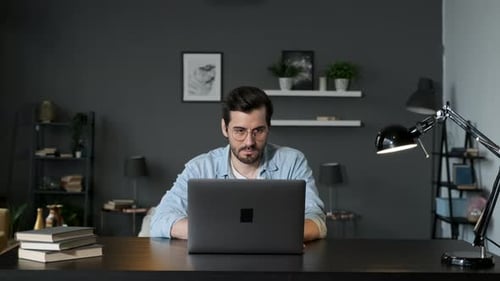Man Working on Laptop at Desk in Home Office