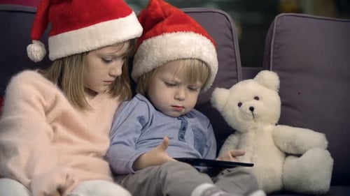 Children Using Tablet Together on Couch at Christmas