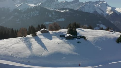 Aerial of cabins in snow covered mountain cliff