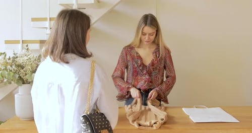 Saleswoman Wrapping Piece Of Clothes For Client