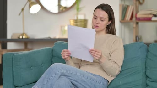 Woman Reading Papers on Sofa Indoors