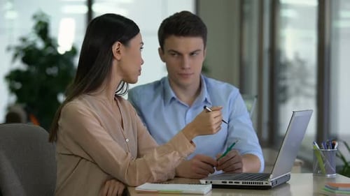 Office Colleagues Collaborate on Laptop Project