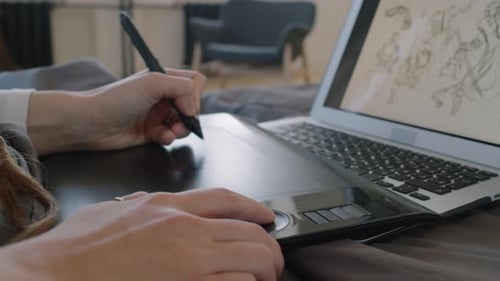 Hand Using Stylus on Drawing Tablet in Bedroom