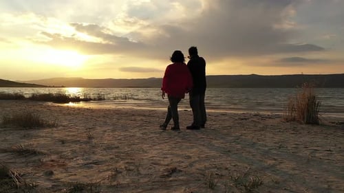 Couple Watching The Sunset By The Lake