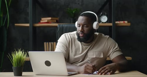 Bearded Man at Desk with Laptop and Headphones