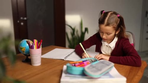 Girl Studying and Writing in Notebook at Desk
