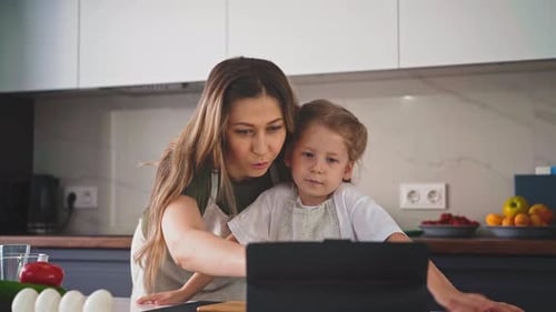 Woman and Child Watch Tablet in Bright Kitchen