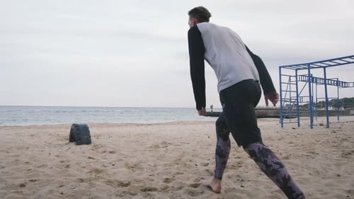 Young Man Doing Parkour Tricks on the Beach Near the Sea