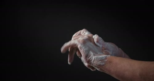 Gros plan des mains moussantes féminines avec du savon avant de se laver sur fond noir