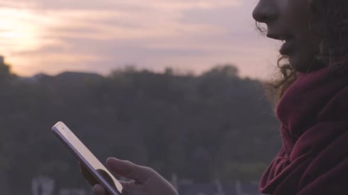 Woman using cellphone at sunrise