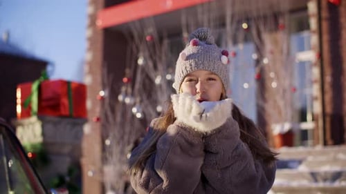 Smiling Girl Blowing Snow Outside on Winter Day