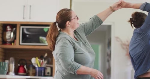 Two Women Dancing Together in Modern Kitchen