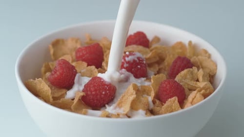 Milk Being Poured Over Cereal and Raspberries