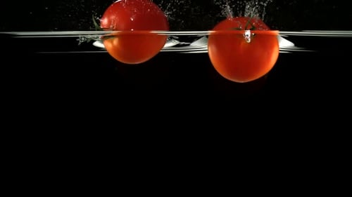 Slo-motion whole tomato falling through water
