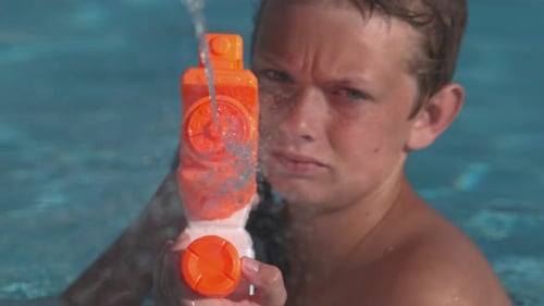 Nahaufnahme eines Jungen, der Wasserpistole in Superzeitlupe sprüht