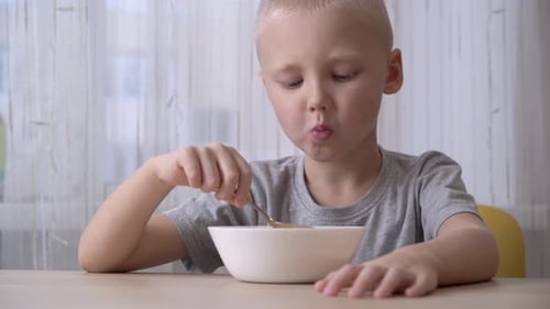 Young Child Eats Food from a Bowl Indoors