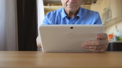 Mature Person Using Tablet Device at Table