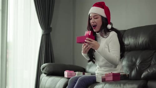 Woman Opening Christmas Gifts at Home