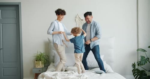 Happy Family Jumping on Bed in Bedroom