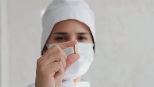 Woman Doctor Holds a Medication Pill Close Up