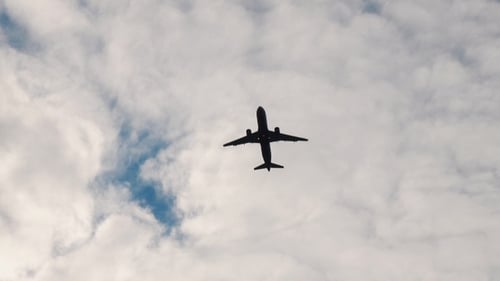 Jet Plane Flies Across Cloudy Blue Sky