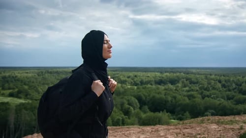 Femme musulmane avec sac à dos contemplant les paysages naturels du sommet de la montagne en profitant de la liberté