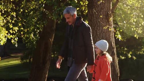 Adult and Child Walking Hand-in-Hand in Park