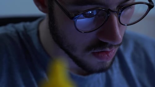 Young Adult with Glasses Working on Computer at Night