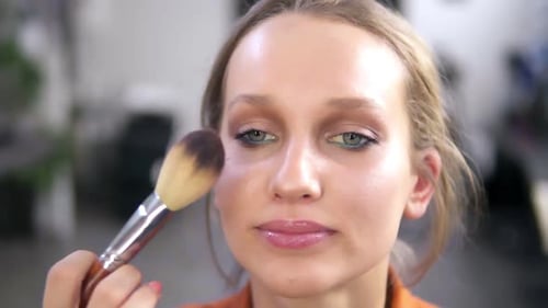 Front View of a Beautiful Smiling Female Model During the Make Up Process
