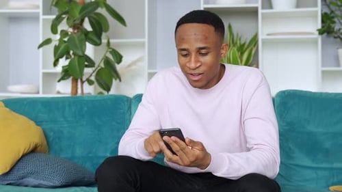 Man on Couch Celebrates While Looking at Phone