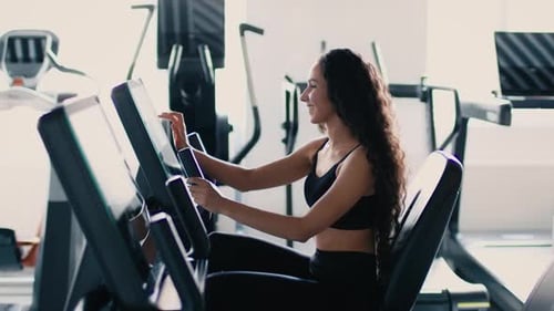 Woman on Exercise Bike in Bright Gymnasium