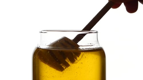 Glass Jar of Honey with Wooden Spoon, Pick It Up, Isolated on White, Slow Motion, Slose Up