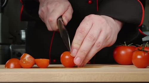 A Cook Cuts A Cherry Tomatoes On A Cutting Board In A Kitchen