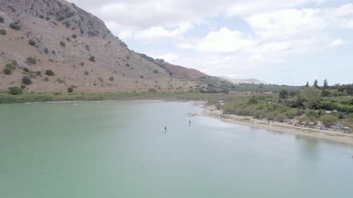 Aerial drone view of the couple rowing a stand-up paddle board SUP on the lake