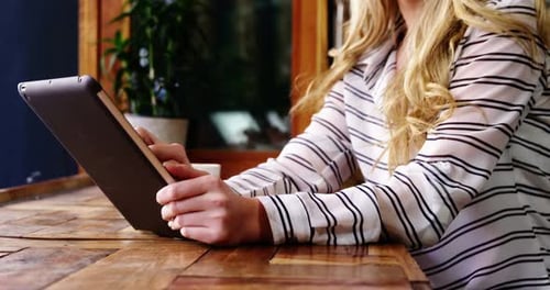 Woman using digital tablet in cafe
