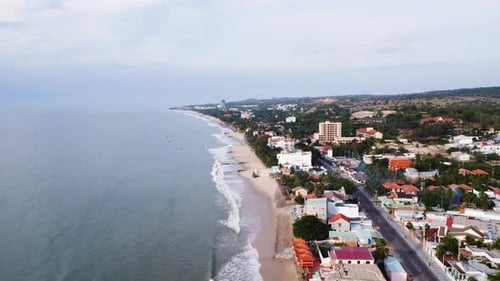 Small coastal town of Vietnam with tiny sandy beach affected by sand loss, aerial drone view