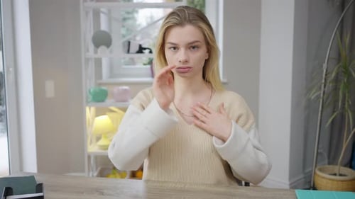 Front View Portrait of Confident Serious Young Woman Showing Sign Language Gestures Sitting at Table