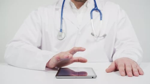 Doctor Using Tablet Device in White Room