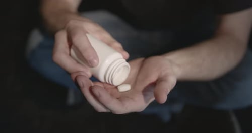 Person Pouring Pills into Hand
