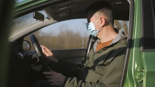 Man in Mask Cleans Car Steering Wheel With Wipe