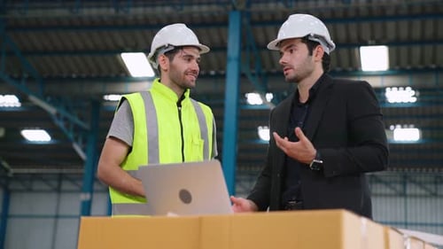 Two Factory Workers Working and Discussing Manufacturing Plan in the Factory
