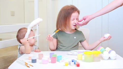 Children Painting Easter Eggs at Table Together