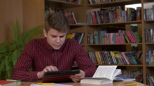 Student Using His Digital Tablet in a Library, Preparing for Abstracts. Close Up, Slow Motion