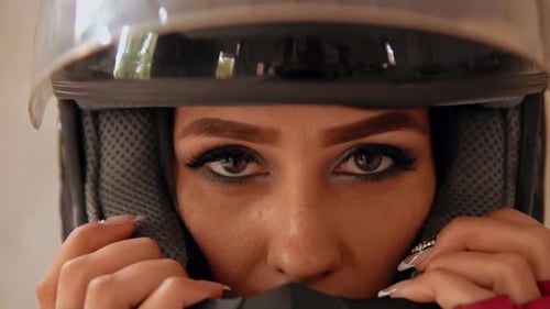 Female with Black Hair Puts On Motorcycle Helmet