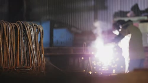 Welder Working With Metal and Sparks in Factory