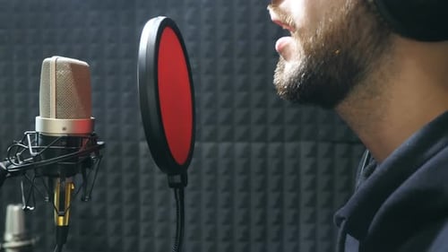 Male Singer in Headphones Singing Song Into the Microphone at Sound Studio