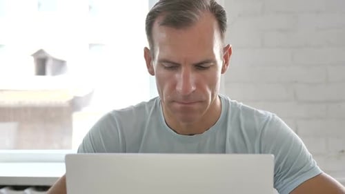 Pensive Man Thinking and Working on Laptop