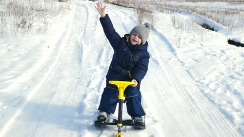 Kleiner Junge reitet einen Schlitten und ein Schneemobil in einem verschneiten Wald