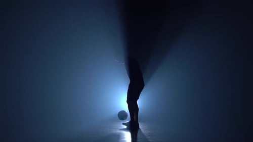 Fútbol estilo libre. Freestyler en Studio Against Blue Spotlight haciendo trucos. Cámara lenta